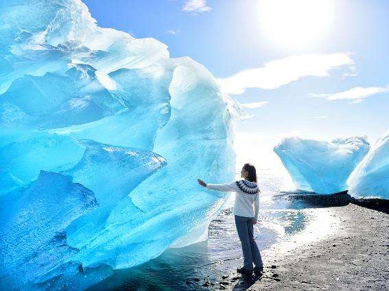 Mujer tocando un glaciar en Jokulsarlon, una de las mejores excursiones de Islandia
