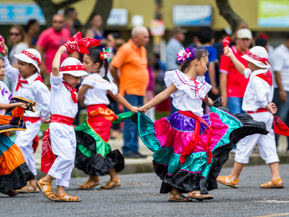 Niños pequeños con ropa tradicional y baile en celebración en el Día de la Independencia, una de las mejores cosas que hacer en Costa Rica