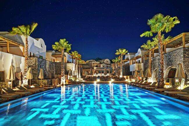 Radisson Blu Zaffron Resort por la noche en la zona de la piscina con diseños limpios en el agua para un post titulado los mejores hoteles de Santorini