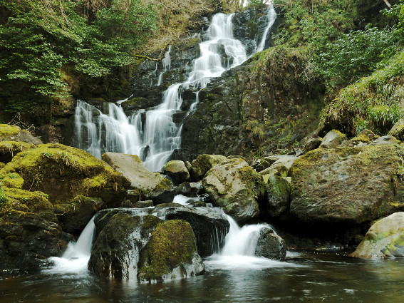 Rocas cubiertas de musgo en la tranquila cascada Torc en Killarney, una pieza de los mejores lugares para visitar en Irlanda