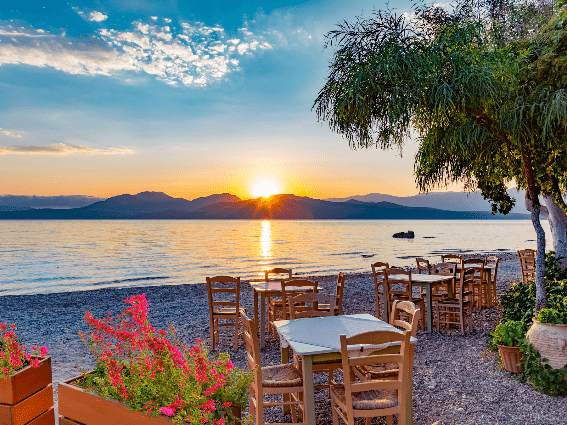 Romántico restaurante en la playa durante un amanecer junto a un mar tranquilo en la isla de Lefkada, una de las mejores islas de Grecia para visitar