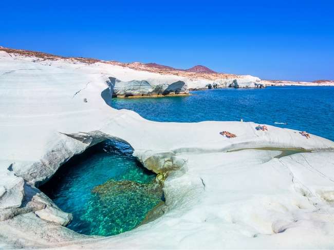 Sarakiniko, Milos, una de las mejores playas de Grecia, vista desde lo alto de las rocas con bañistas junto al agua azul