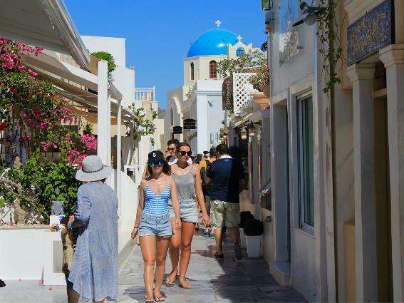 Turistas jóvenes en Santorini caminando bajo el sol durante el verano