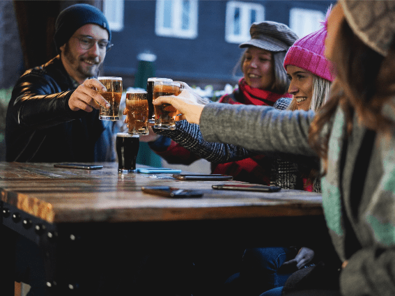Un feliz grupo de amigos brindando por la cerveza en un pub, uno de los mejores lugares para visitar en Irlanda