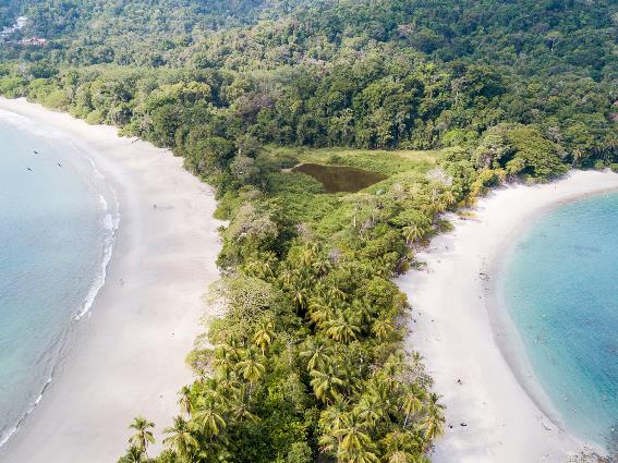 Vista aérea de personas nadando en las aguas cristalinas de playa Manuel Antonio, considerada como una de las mejores playas de Costa Rica debido a su arena blanca y amplia zona de costa