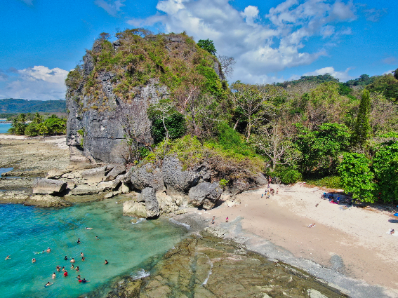 Vista aérea de una enorme roca y gente nadando en las aguas cristalinas de Santa Teresa y Playa Malpaís, una pieza en las mejores playas de Costa Rica