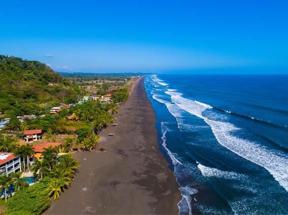 Vista aérea en una de las mejores playas de Costa Rica, Playa Hermosa con su arena fina y oscura, altas palmeras y olas tranquilas