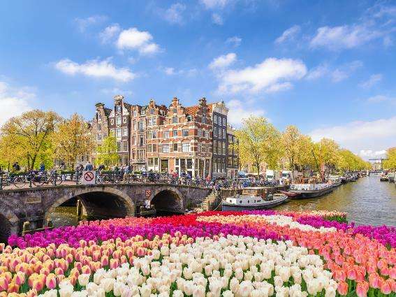 Ámsterdam en la foto durante el mejor momento general para visitar con tulipanes en plena floración, clima cálido y cielos azules